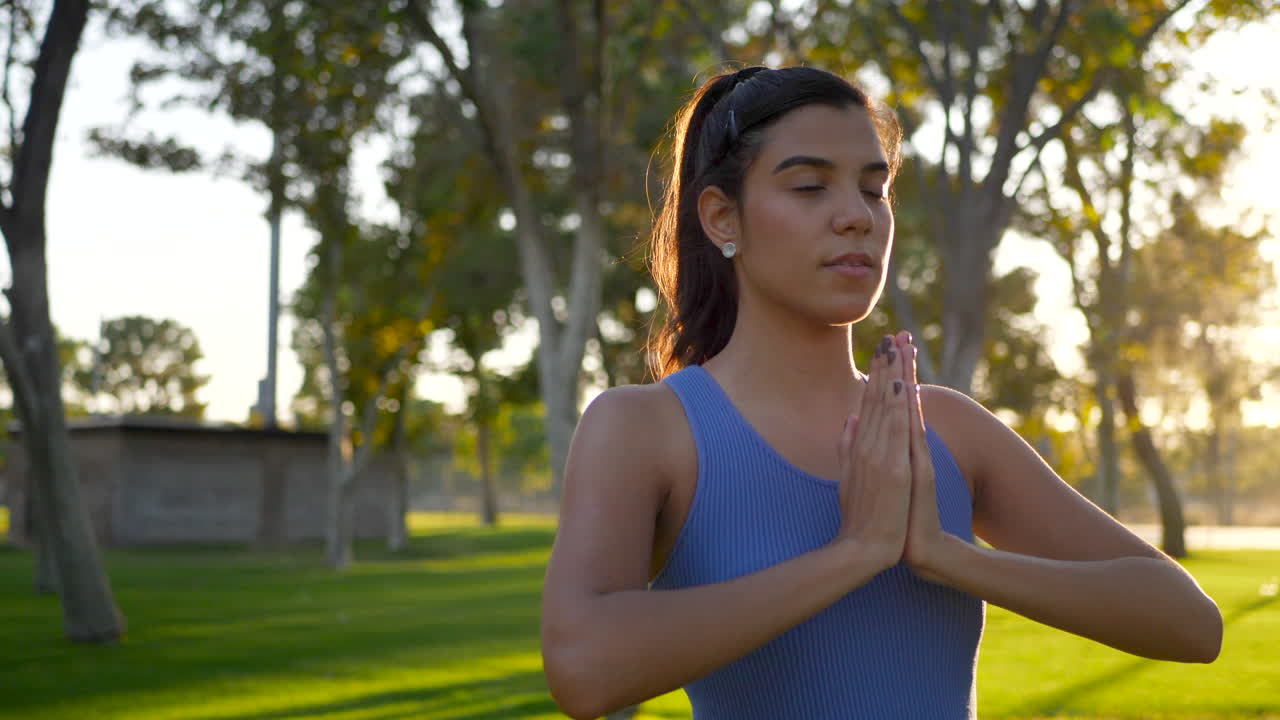 una hermosa joven hispana yogui meditando en una pose de manos de oración de una pierna en el parque al amanecer