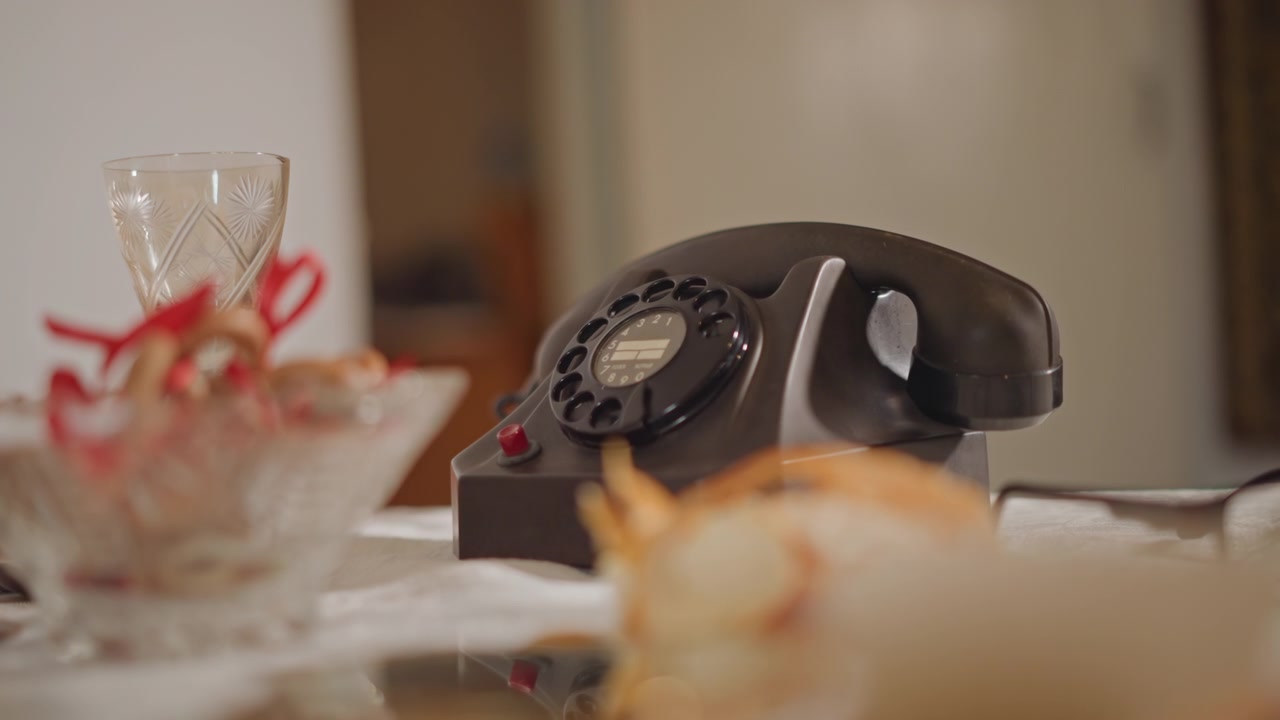 Classic rotary phone on decorated dinner table creating nostalgic atmosphere. Antique rotary telephone paired with decorative bowl and soft lamp light evoking retro charm and domestic quiet