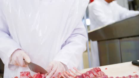 female butcher cutting raw meat