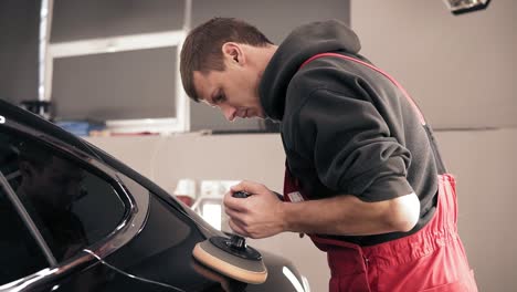 el trabajador masculino pulió suavemente la parte trasera de un coche negro.