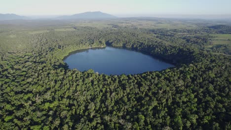 tranquilo lago de cráter rodeado de exuberante selva tropical - lago eacham en atherton tableland, queensland, australia - toma aérea