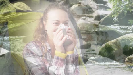 animation of caucasian woman drinking tea in tent over river and rocks