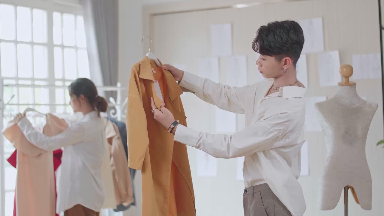 Young Man Fashion Designers Looking At Clothes At Fashion Design Studio