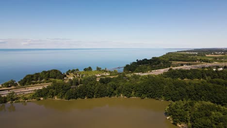 Aerial-view-of-a-cars-driving-on-a-highway-on-the-shore-of-Lake-Ontario-and-Sixteen-Mile-Pond