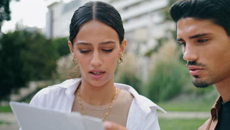 pareja latina leyendo documentos al aire libre de cerca. compañeros de trabajo serios trabajando en el parque
