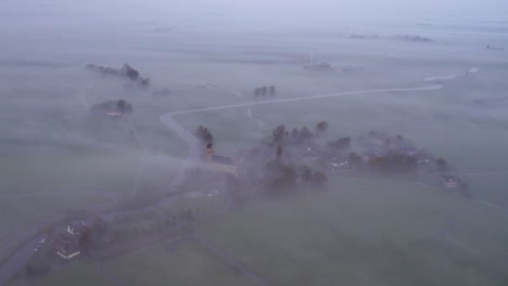 side panning shot of church hichtum covered in morning fog, aerial