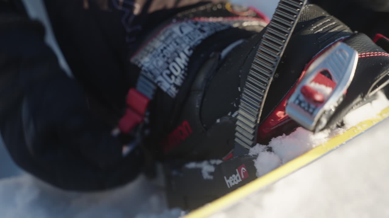 4k close up of snowboarder getting ready attaching boot to the snowboard and fasting and securing the straps