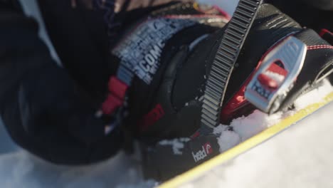 4k close up of snowboarder getting ready attaching boot to the snowboard and fasting and securing the straps