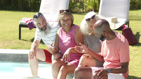 relaxing by pool, senior friends laughing and enjoying conversation outdoors