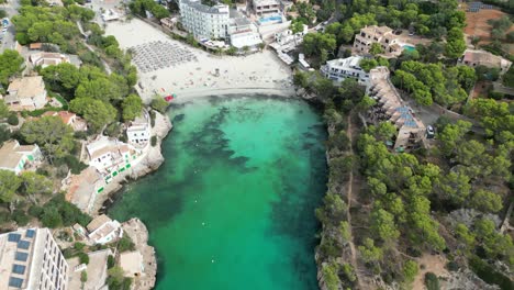 Isolated-beach-surrounded-by-blue-and-green-water-in-Mallorca,-aerial