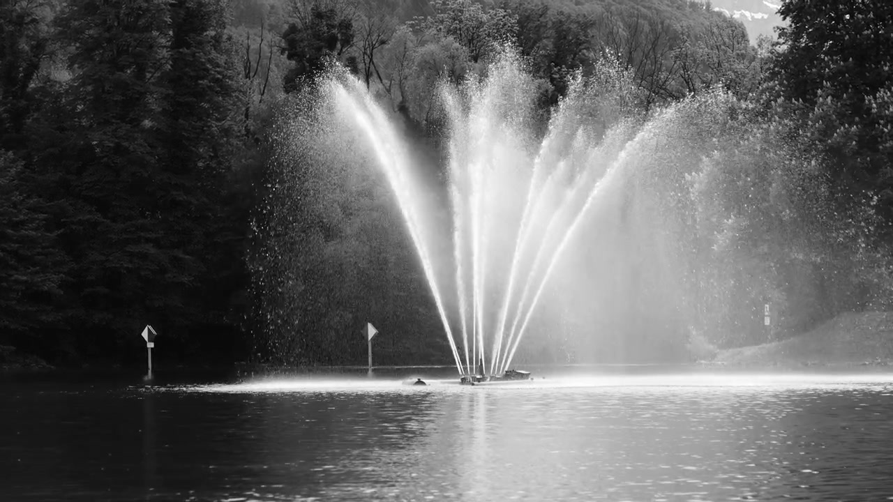 Chorro de fuente cinematográfico en lago, ideal para branding de lujo, fondos tranquilos y visuales elegantes para narración de historias