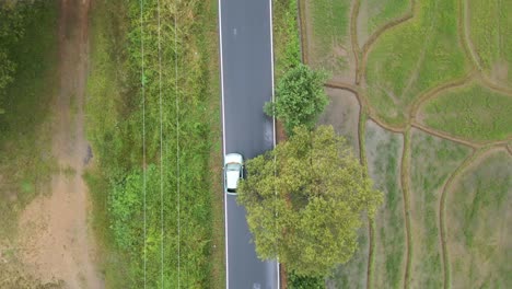 Top-Down-shot-of-a-car-traveling-down-a-wet-back-country-road-in-Mahiyangana