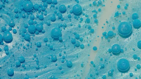 top view movement of blue oil ink drops bubbles, multicolored artistic paint surface background