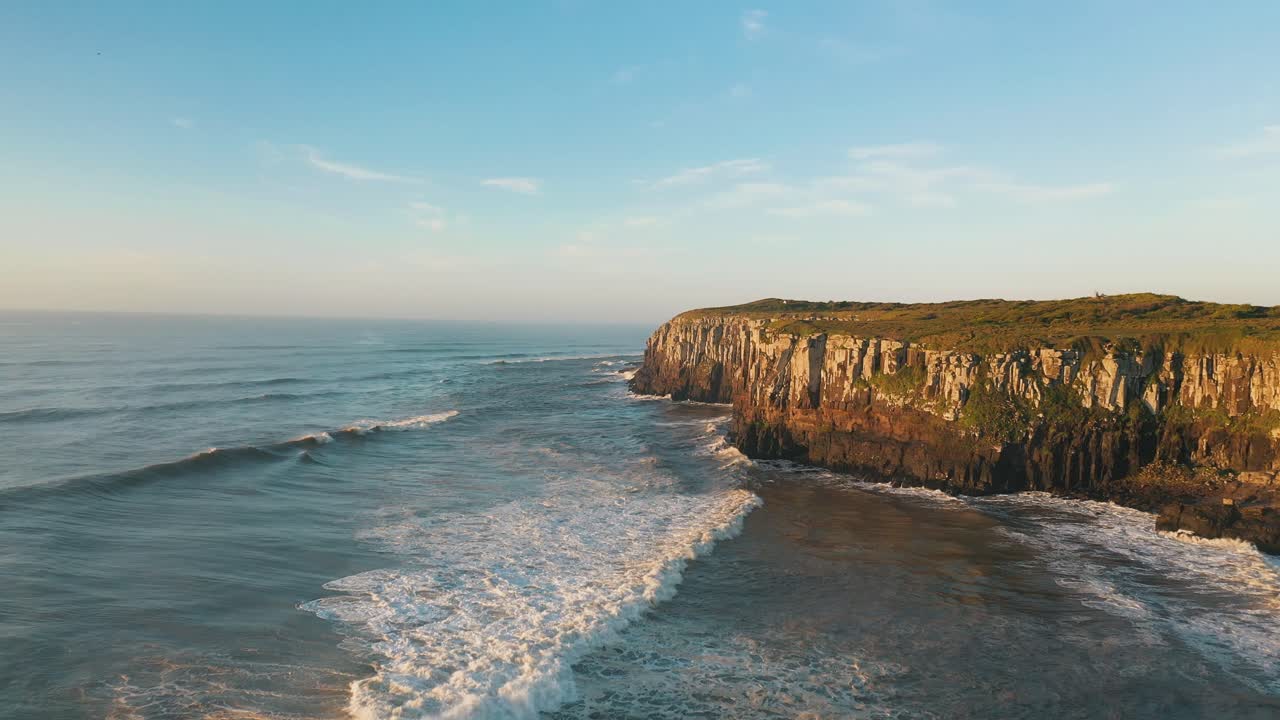 Drone aerial view of tropical beach rocky cliffs on atlantic ocean at sunrise