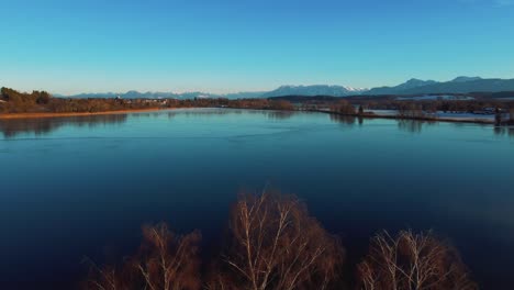 Vuelo-De-Drones-Aéreos-De-4k-Uhd-Avanzando-Sobre-Un-Lago-Congelado-Helado-Y-Copas-De-árboles-En-Baviera-Cerca-De-Los-Alpes-En-Invierno-En-Alemania-Cerca-De-Austria