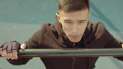 man doing bar pull-up on workout playground