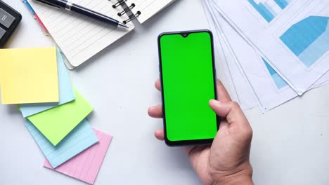 top view of man hand using smart phone on office desk