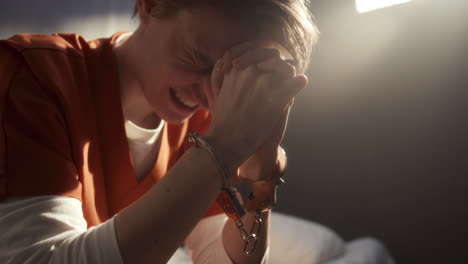 female inmate in handcuffs crying in despair in prison cell