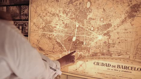 person pointing at a historical map of barcelona