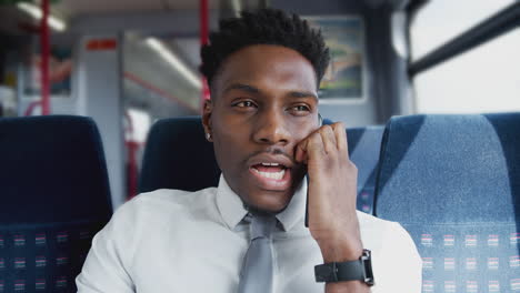 businessman sitting in train commuting to work talking on mobile phone