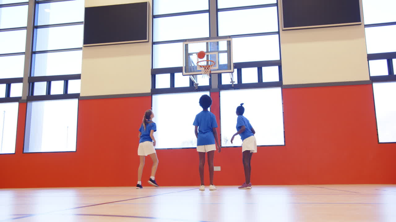 Playing basketball in school gym, kids aiming for hoop during game