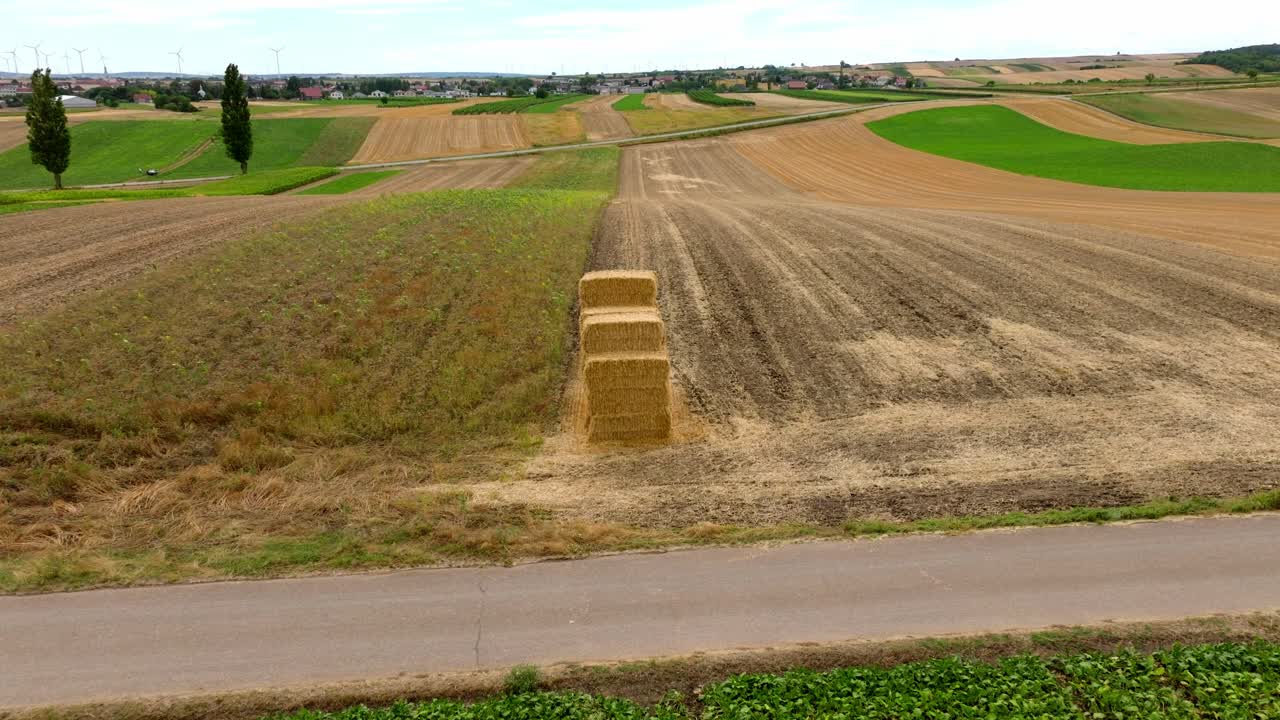 vista aérea de balas de heno cuadradas en las tierras de cultivo con el parque eólico en el fondo