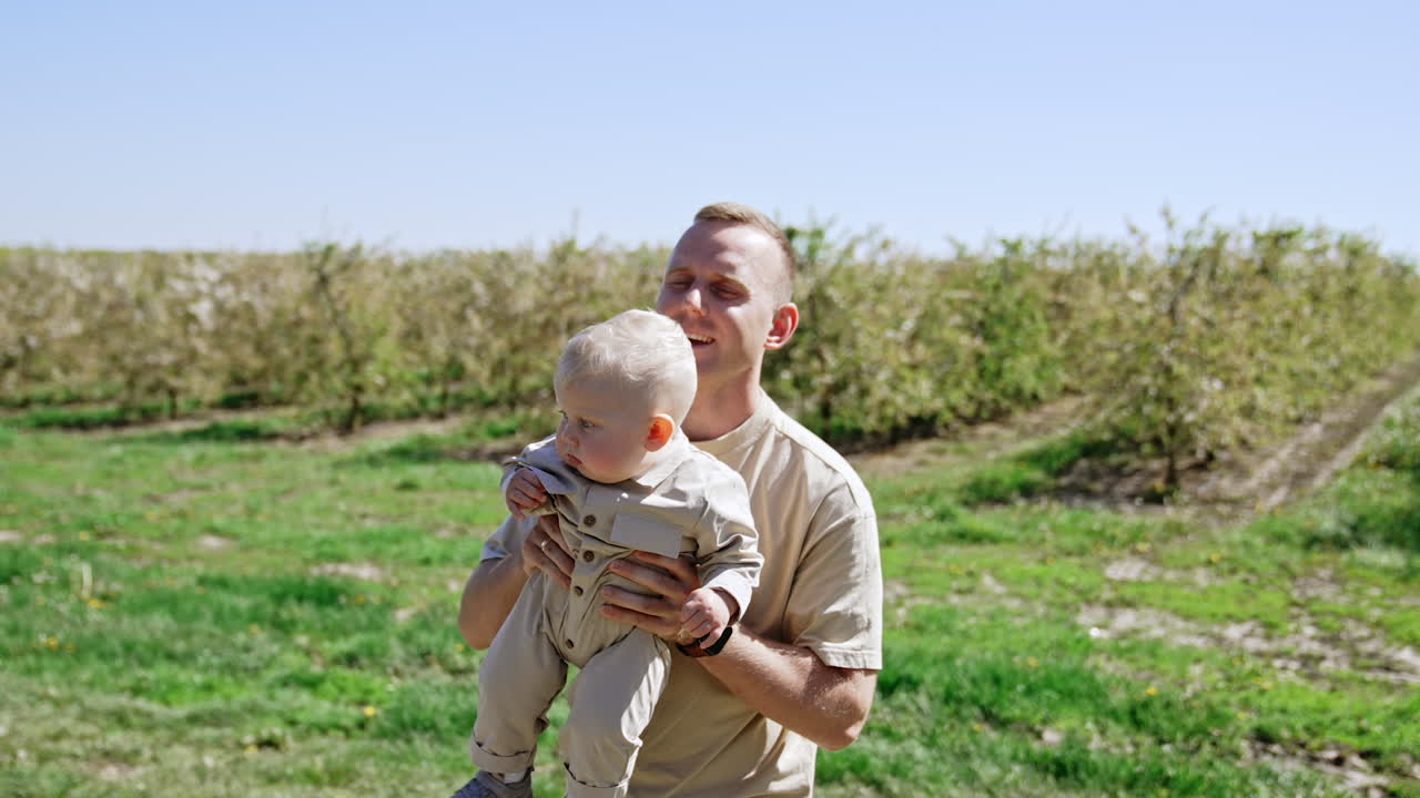 Mid-aged Caucasian man with his infant baby. Father and son spend time in the nature on sunny day.