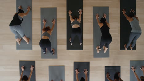 above-view-yoga-class-instructor-teaching-warrior-pose-to-group-of-women-enjoying-healthy-lifestyle-exercising-in-fitness-studio