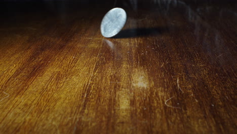 closeup of coin flipping of wooden table, 10 cent italian lira, static, slow