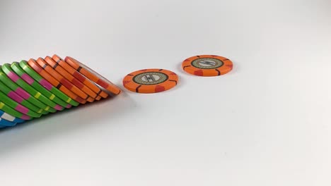 Stack-of-colorful-poker-chips-falling-down-from-left-side-on-a-white-table,-ISOLATED,-STILL