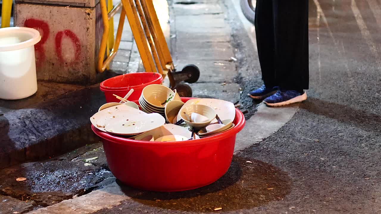 vendedor lavando platos en una calle de hanoi