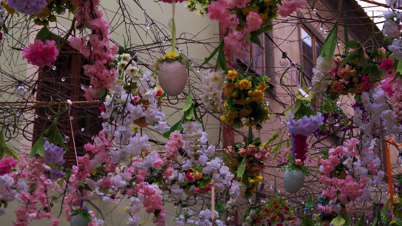 Colorful Easter flowers and hanging eggs spanning narrow alley, looking up through decoration, Czech Republic