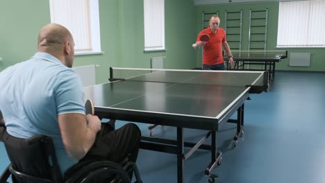 a man in a wheelchair plays ping pong. people with disabilities play table tennis. rehabilitation of the disabled. paralympic sport.