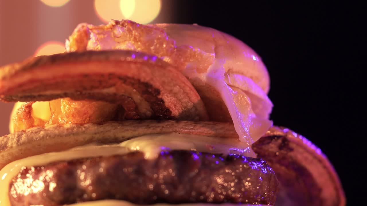 hamburguesa gourmet con tocino crujiente girando en un clip similar a un anuncio con relámpagos de neón