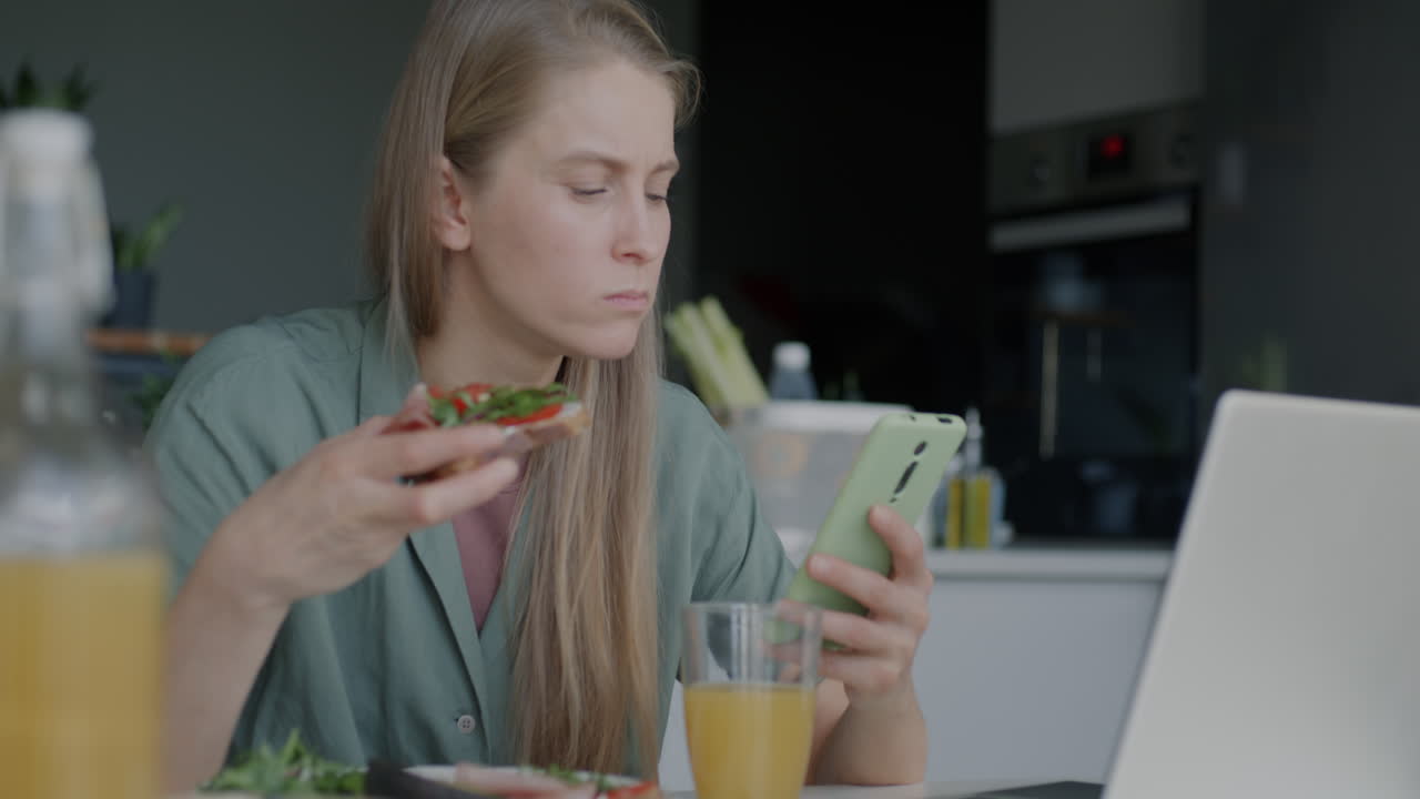 Woman eating lunch and using phone at home