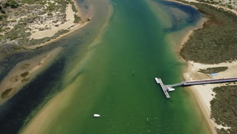 boats and pier on tranquil river in cabanas de tavira at the atlantic ocean coastline in algarve, portugal