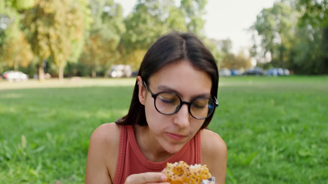 mujer comiendo una hamburguesa en un parque