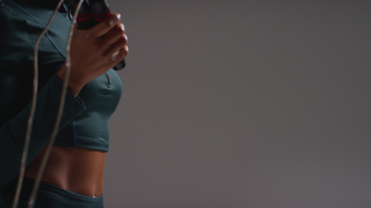 평평한 배경에 점프 로프 또는 점핑 로프와 함께 체육관 피트니스 클래스에서 운동복을 입은 여성 운동 선수의 근접 촬영 2