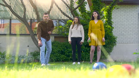 Front-view-of-caucasian-group-of-women-and-men-friends-playing-petanque-in-the-park-on-a-sunny-day