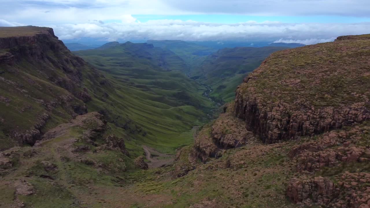 toma de drones de drakensberg en sudáfrica: el drone está en la cima de la montaña y revela el valle del paso sani.