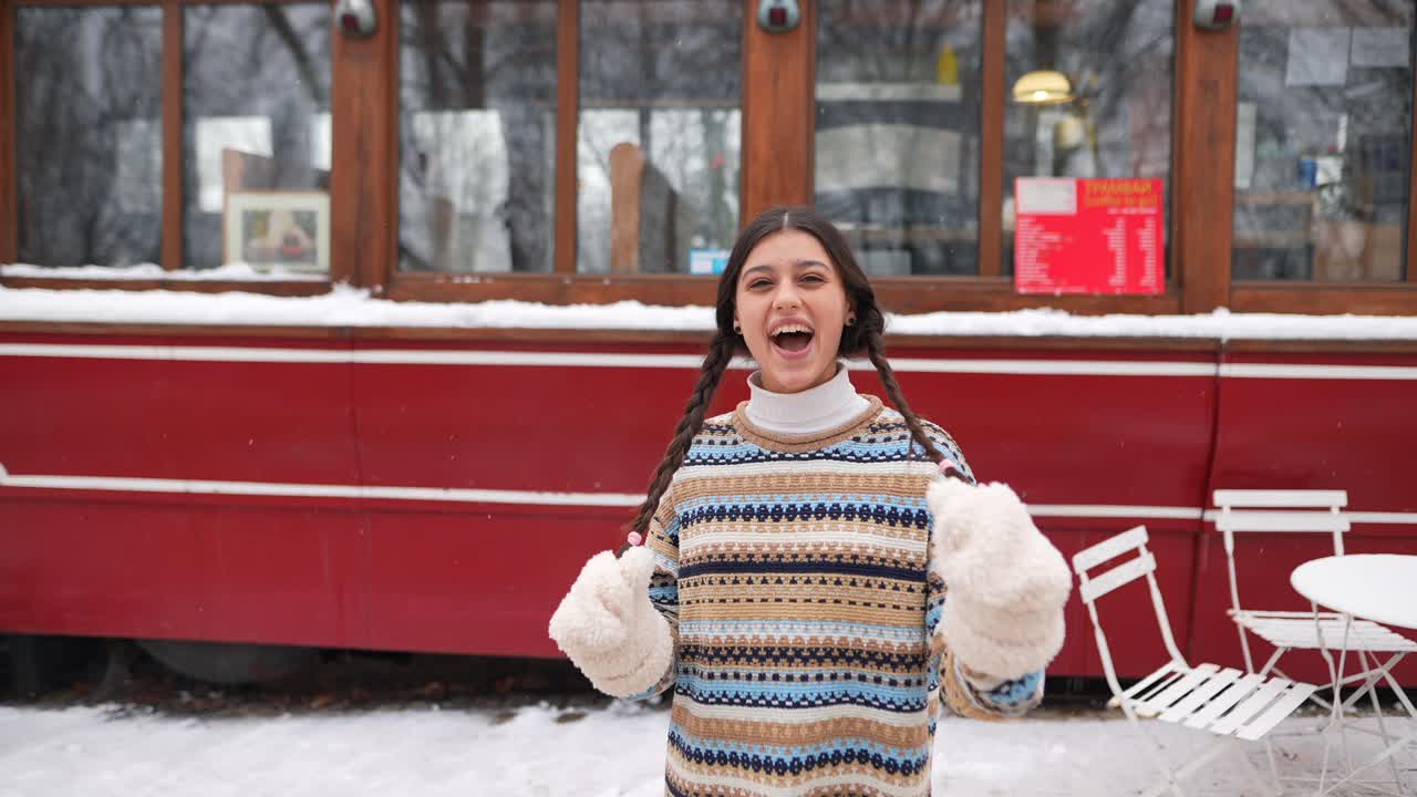 Woman in winter clothes, smiling in front of a red tram