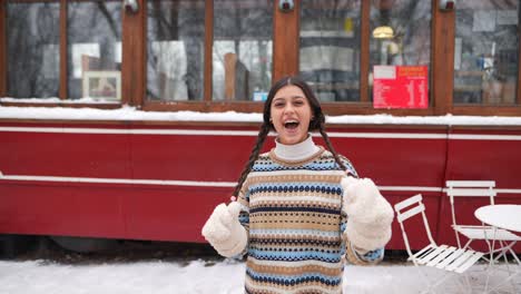 woman in winter clothes, smiling in front of a red tram