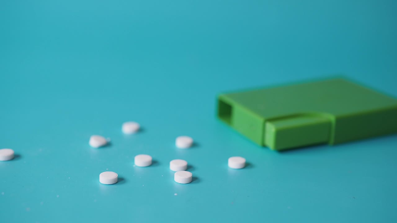 pastillas blancas en un recipiente verde sobre un fondo azul