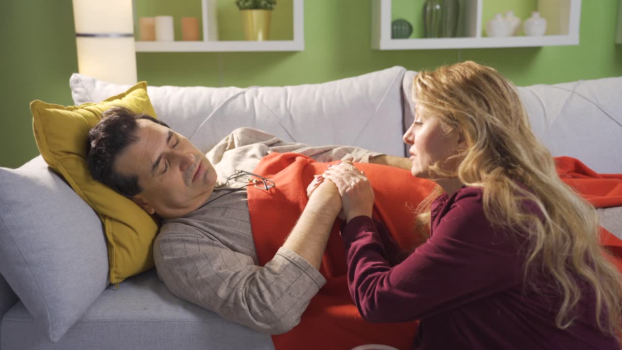 매우 아픈 성숙한 남자는 집에서 그의 충성스럽고 사려 깊은 아내에 의해 사기를 얻습니다. 여자는 아픈 남편을 사랑합니다.