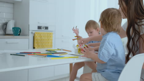 two children of boys and mother are engaged in creative development doing homework by fingering on paper. the development of tactile sensations and small mathematics.