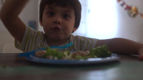 imágenes de primer plano de un niño comiendo hamburguesas de ternera y brócoli en casa