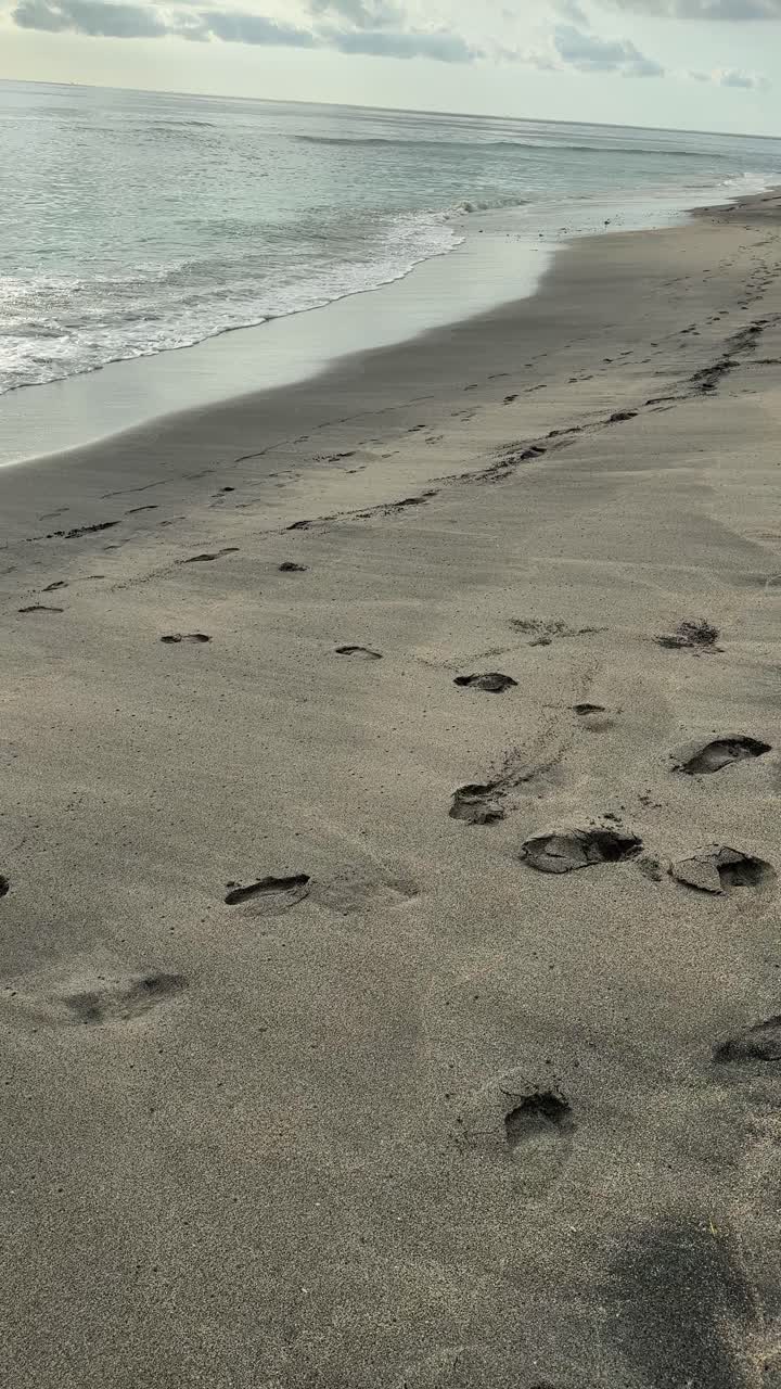 Impronte su spiaggia sabbiosa con dolci onde dell'oceano.