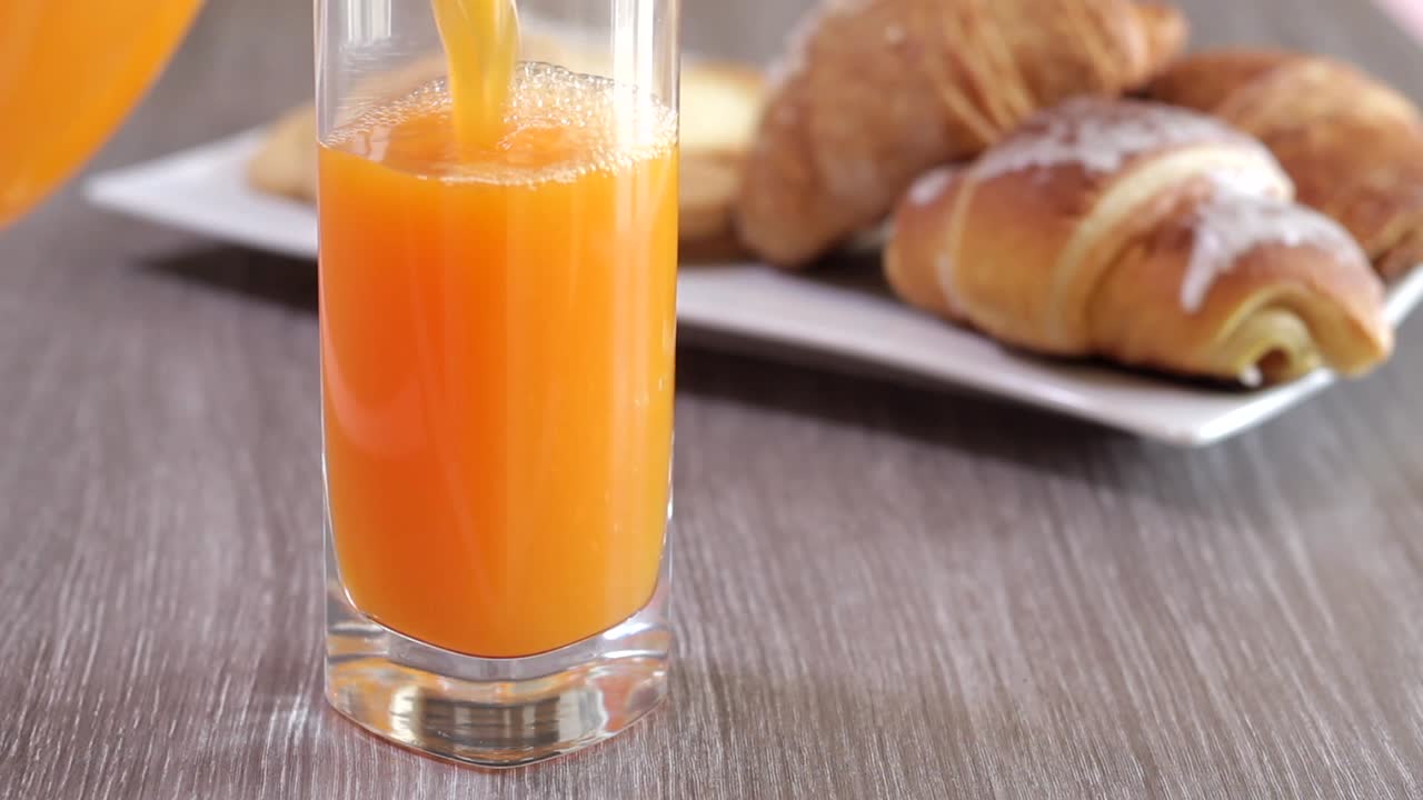 versando il succo d'arancia in un bicchiere per colazione al mattino