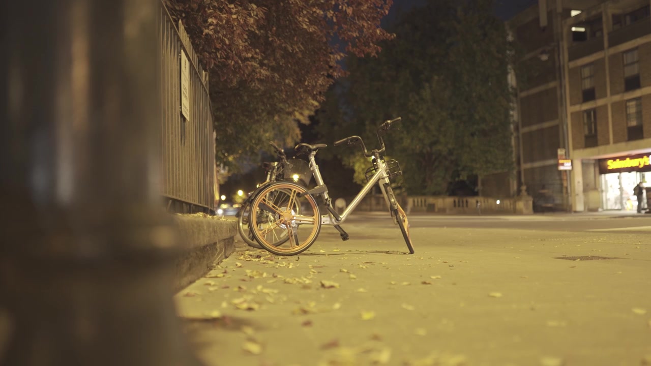 4K timelapse on motion slider showing a bicycle parks on a busy road as cars, buses, bikes and pedestrians move by quickly.
