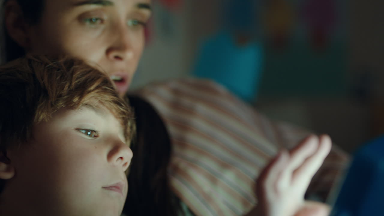 niño feliz usando una computadora tablet con su madre enseñando a su hijo jugando juegos en la tecnología de pantalla táctil divirtiéndose antes de acostarse